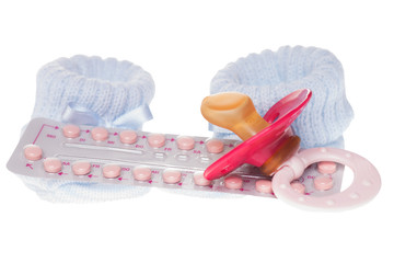 Antibabypille mit Nuckel und Babyschuhen isoliert