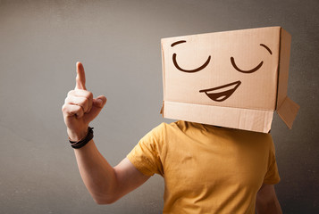 Young man gesturing with a cardboard box on his head with smiley