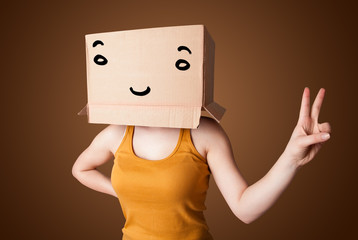Young woman gesturing with a cardboard box on her head with smil