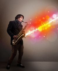 Young man playing on saxophone with colorful sound waves
