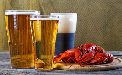 Tasty boiled crayfishes and beer on old table