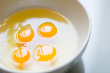 Four yellow egg yolks in a white bowl.