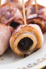 Baked prunes in bacon on a plate
