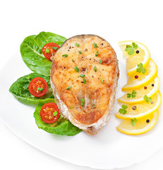 Fish dish- fried fish fillet with vegetables on white background