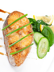Fish dish -fried fish fillet with vegetables on white background