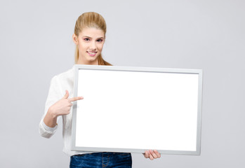 Fototapeta premium Young student girl smiling and pointing to a blank white board.