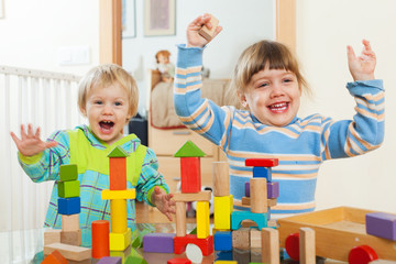 Two happy children playing with  blocks  in home