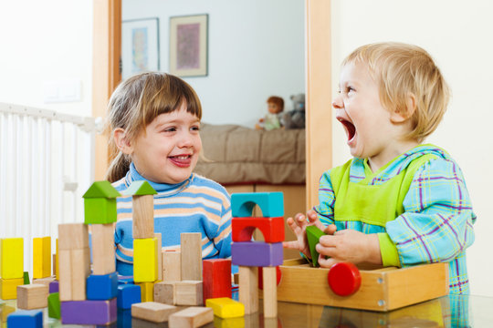 Emotional happy siblings playing with wooden toys