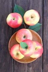ripe juicy apples in a wooden plate on an old table