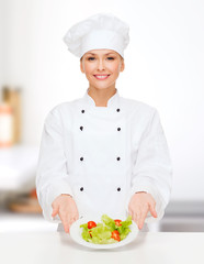 smiling female chef with salad on plate