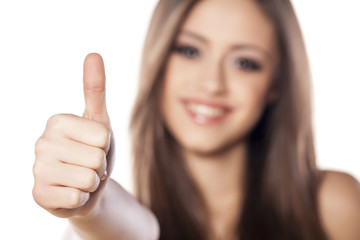 Smiling girl showing thumb up on white background