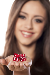 smiling girl holding a pair of dice for gambling