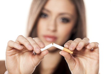 serious girl breaks a cigarette with a focus on the foreground - obrazy, fototapety, plakaty