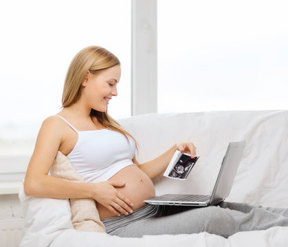 smiling pregnant woman with laptop computer