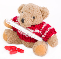 Sick teddy bear with thermometer isolated on white