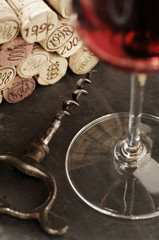 Corks of different wine years and glass of red wine