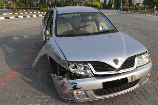 An Abandoned Wrecked Car At A Parking Lot