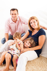 Beautiful happy family sitting on the carpet.