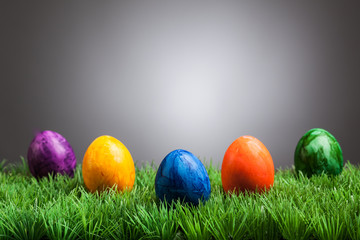 Colored easter eggs in grass, gray background