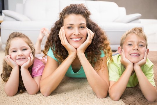 Happy siblings lying on the rug posing with their mother