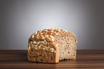 Loaf and slice of wholemeal bread on table