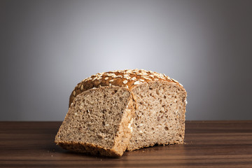 Loaf and slice of wholemeal bread on table
