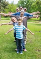 Fototapeta premium Extended family standing in row with arms outstretched at park