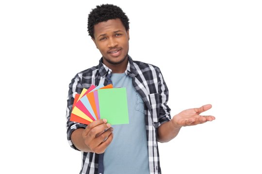 Portrait Of A Confused Man Holding Colorful Papers