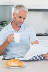 Happy man reading the newspaper at breakfast