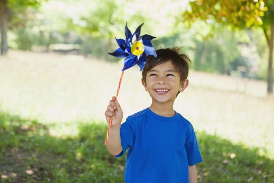 Happy cute little boy holding pinwheel at park