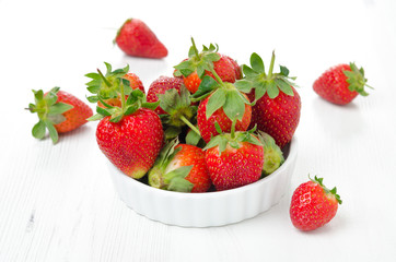 Fresh ripe strawberries in a bowl on a white table