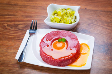 Tasty steak tartare on the plate with egg yolk