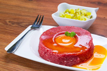 Tasty steak tartare on the plate with egg yolk