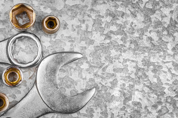 Wrench tools and nuts on a metallic background