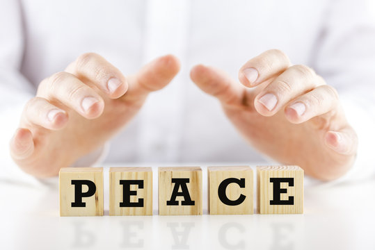 Man holding protective hands above the word Peace
