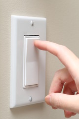 Woman hand turning on the light with a wall switch