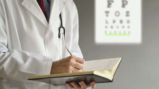 Male ophthalmologist doctor writing prescription to patient afte