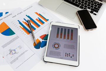 Financial charts on the table with tablet phone and pen