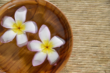 Fototapeta na wymiar frangipani flower in wooden bowl on Brown straw mat