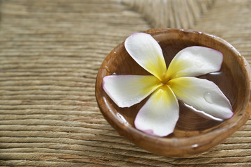 Fototapeta na wymiar frangipani flower in wooden bowl on Brown straw mat