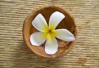 Obraz na płótnie Canvas White frangipani flower in water wooden bowl on mat