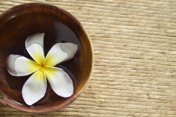 Obraz na płótnie Canvas White Plumeria flower in wooden bowl on mat
