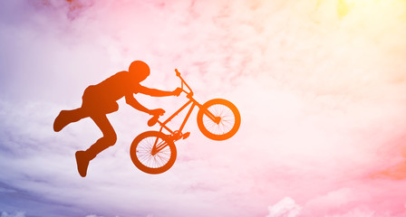 Man doing an jump with a bmx bike against sunshine sky.