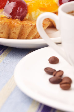 A fragment of a white cup with coffee beans and a tartlet
