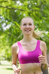 Healthy and beautiful woman in sports bra jogging in park