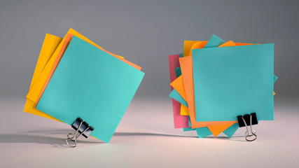 Paper notes fastened with paper clips on gray background.