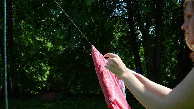 houseworker woman hang washed laundry on clothes-line and clip