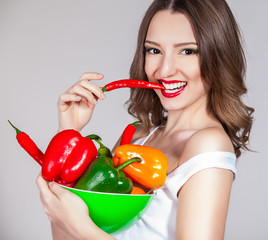 portrait of an attractive young woman holding up peppers