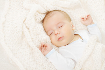 newborn baby sleeping, covering in soft woolen blanket