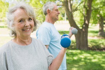 Mature couple using dumbbells at park